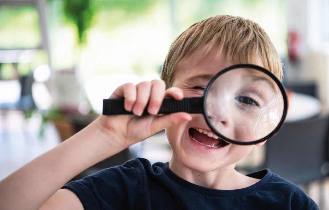 article thumb - A young boy looking through a magnifying glass.